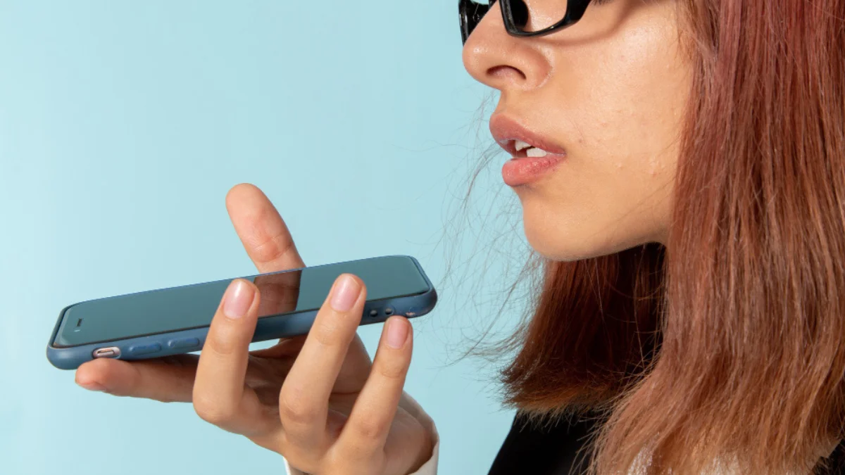 A person with glasses holds a smartphone