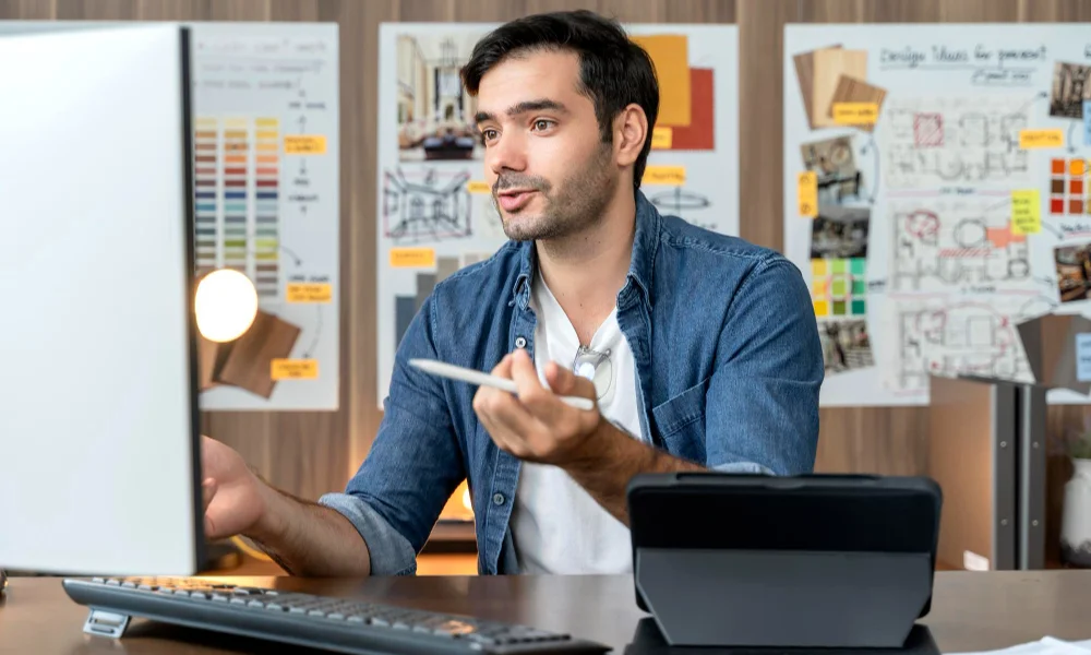 man in a denim shirt sits at a desk-personal branding freelancers