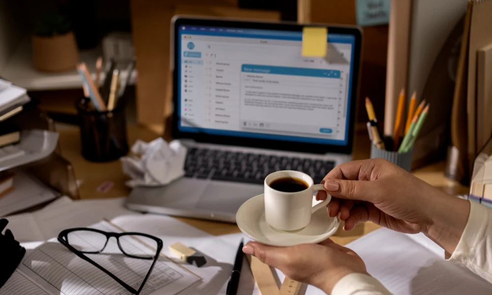 Hands holding a coffee cup in a cluttered workspace-email deliverability news