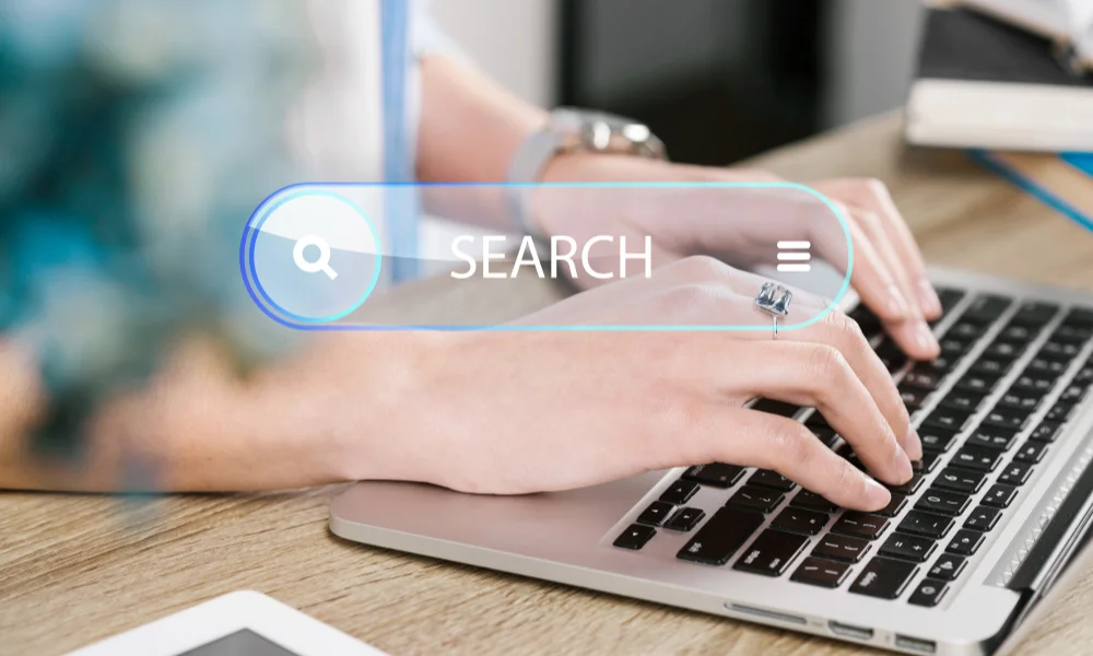 Hands typing on a laptop keyboard with a digital search bar-seo for beginners