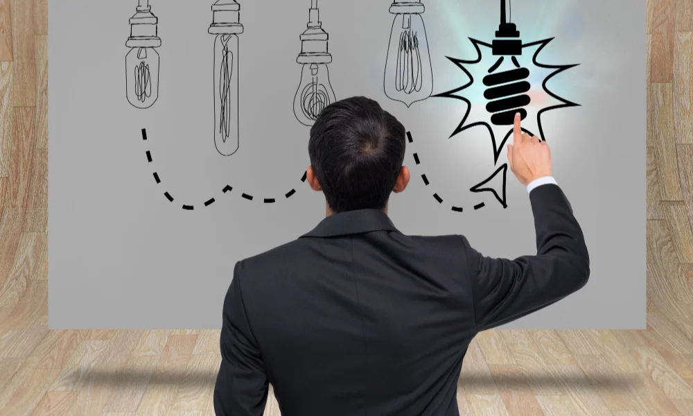A man in a suit points at a series of sketched lightbulbs-personal branding freelancers