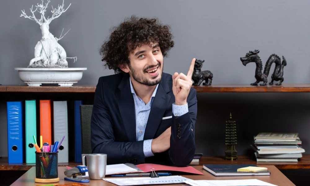 man with curly hair sits at a desk