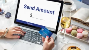 A person holds a credit card near a laptop