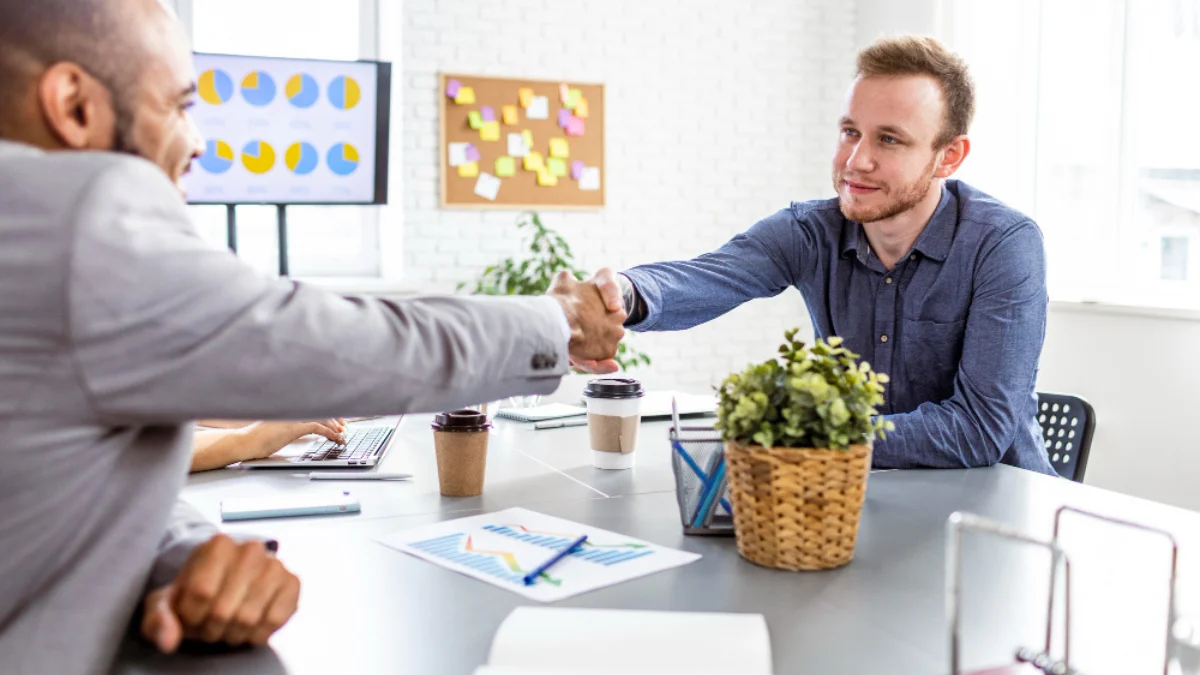 Two men in a bright office setting shake hands